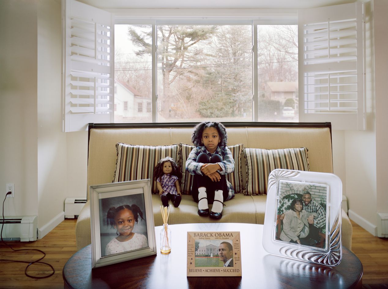 Young girl with her lookalike doll sitting in the living room, environmental portrait photography, Ilona Szwarc, contemporary Los Angeles artist.
