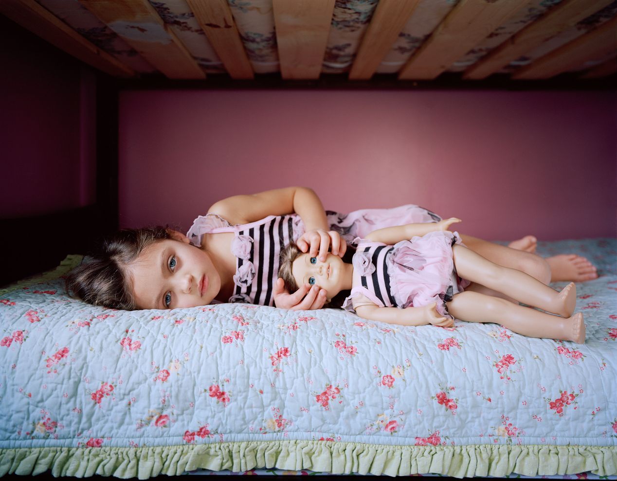 A young girl holding her doll's eyes open, environmental portrait photography, Ilona Szwarc, contemporary Los Angeles artist.
