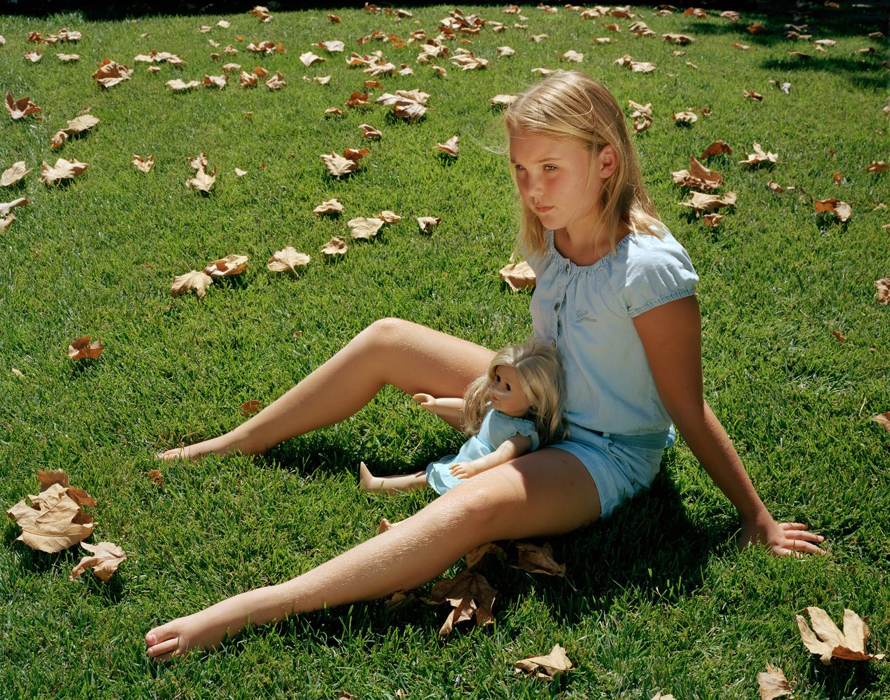 Young girls sitting on the grass with her lookalike doll, environmental portrait photography, Ilona Szwarc, contemporary Los Angeles artist.