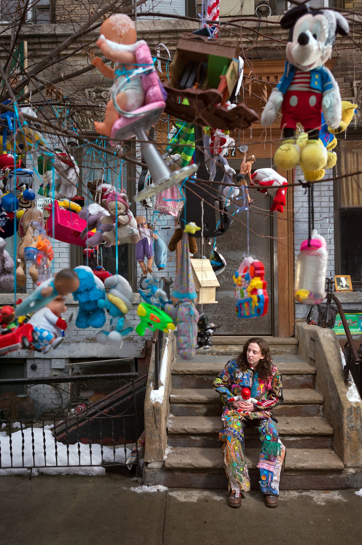 Woman sitting on steps next to a tree decorated with toys, editorial photography, Ilona Szwarc, Los Angeles portrait photographer.