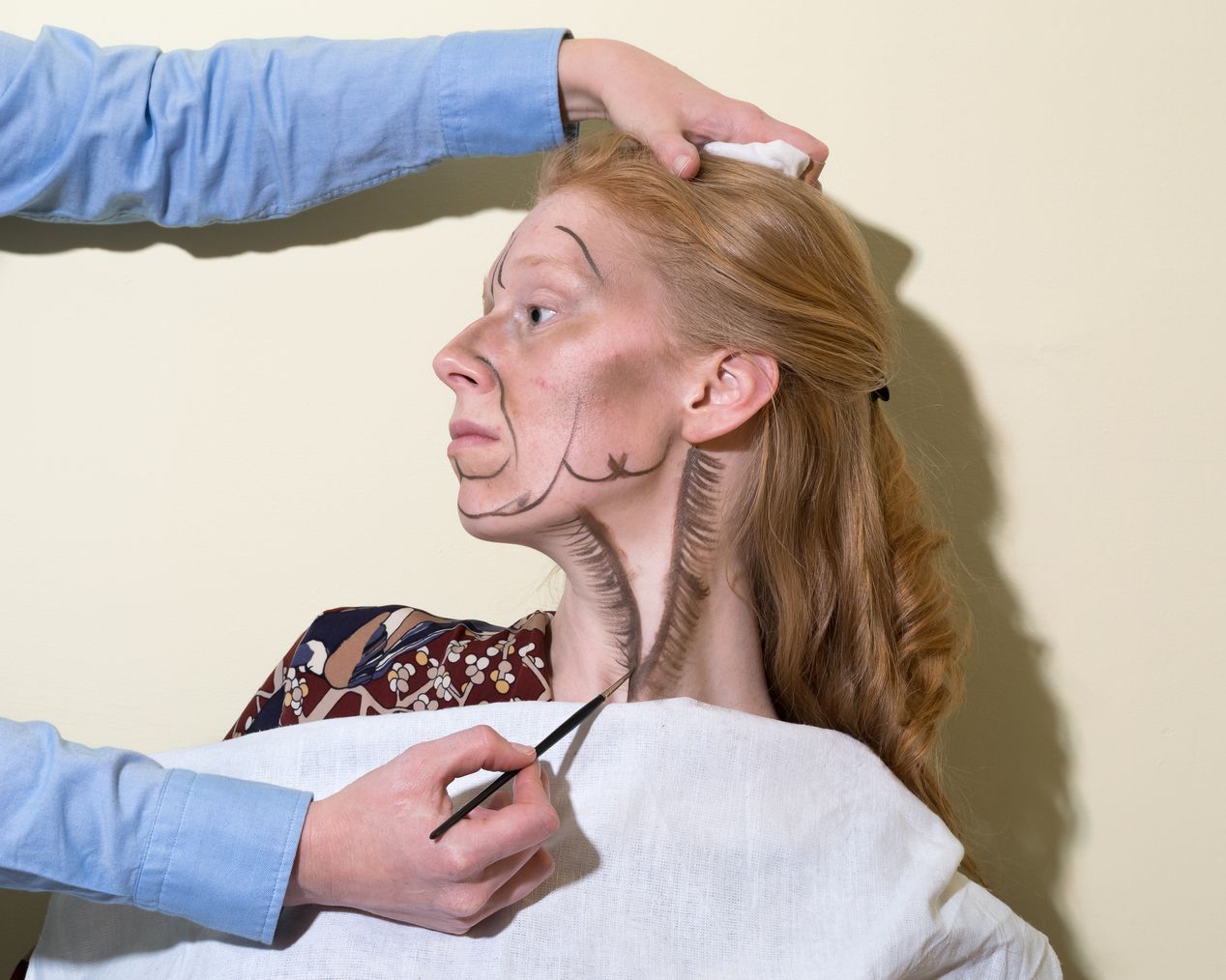 Makeup artist is painting smaller lines on the model's neck, art photography, Ilona Szwarc, contemporary Los Angeles artist.