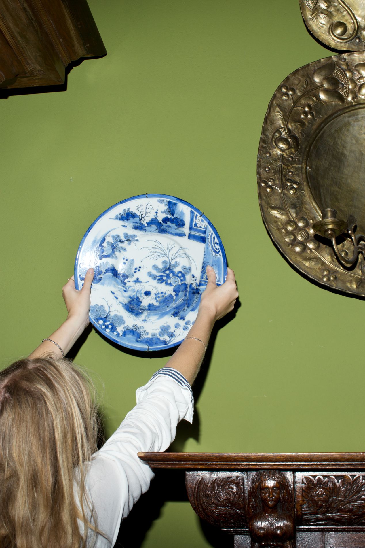A woman holding a porcelain plate against a green wall, fine art photography, Ilona Szwarc, contemporary Los Angeles artist.