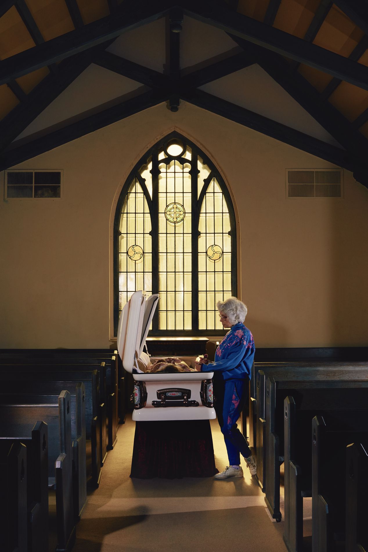 A female mortician near a casket in a chapel, staged photography, Ilona Szwarc, Los Angeles editorial photographer.