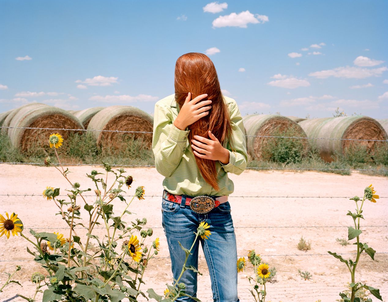 Teenage girl touching her hair, standing in the field, environmental portrait photography, Ilona Szwarc, contemporary Los Angeles artist.