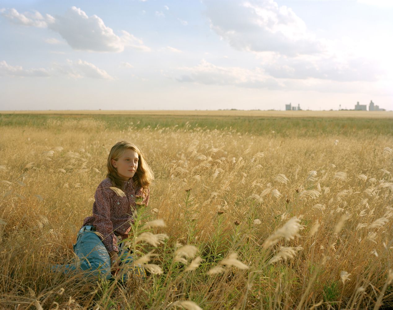 Young rodeo girl sitting in a yellow crop field, environmental portrait photography, Ilona Szwarc, contemporary Los Angeles artist.