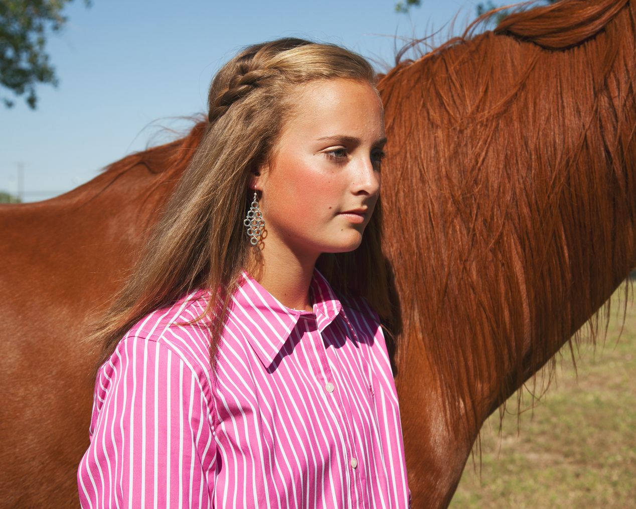 Teenage rodeo girl posing next to her brown horse, environmental portrait photography, Ilona Szwarc, contemporary Los Angeles artist.