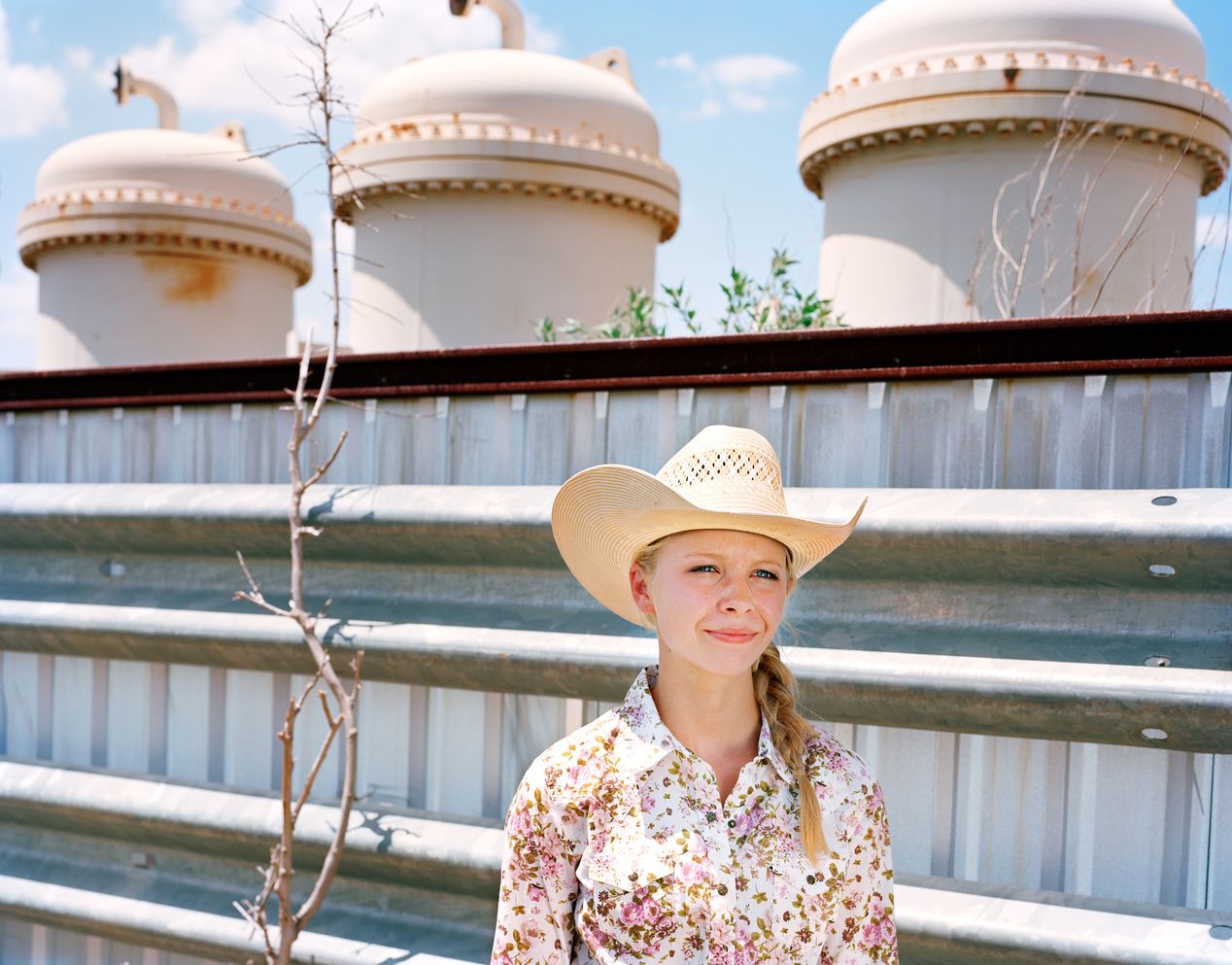 Teenage rodeo girl posing next to silos, environmental portrait photography, Ilona Szwarc, contemporary Los Angeles artist.