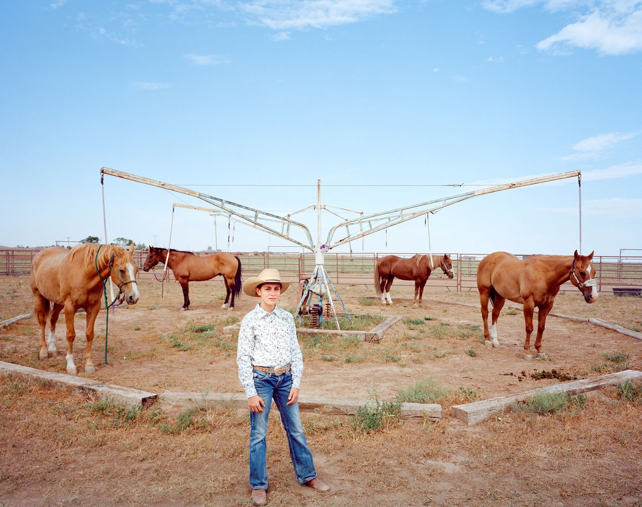 Young cowgirl standing in front of a horse walker, environmental portrait photography, Ilona Szwarc, contemporary Los Angeles artist.