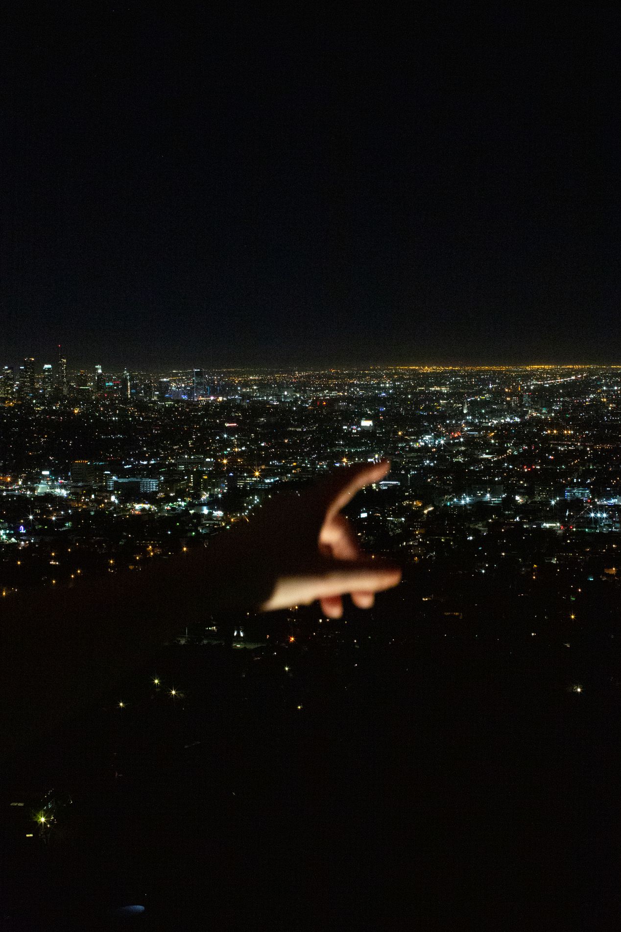 A hand pointing to a horizon at night, Ilona Szwarc, Los Angeles editorial photographer.