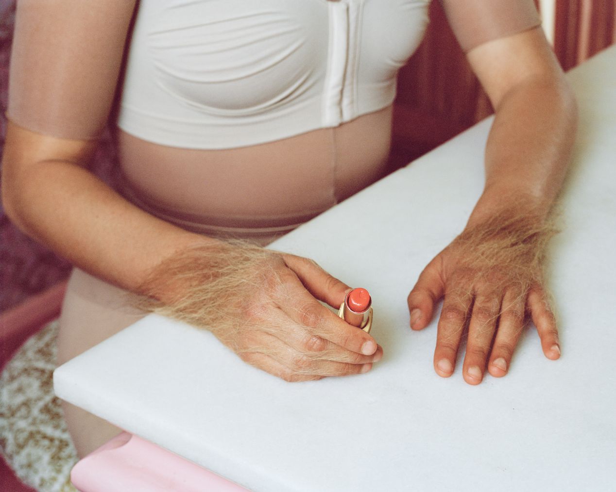 Hands covered with excess hair are holding a red lipstick, art photography, Ilona Szwarc, contemporary Los Angeles artist.