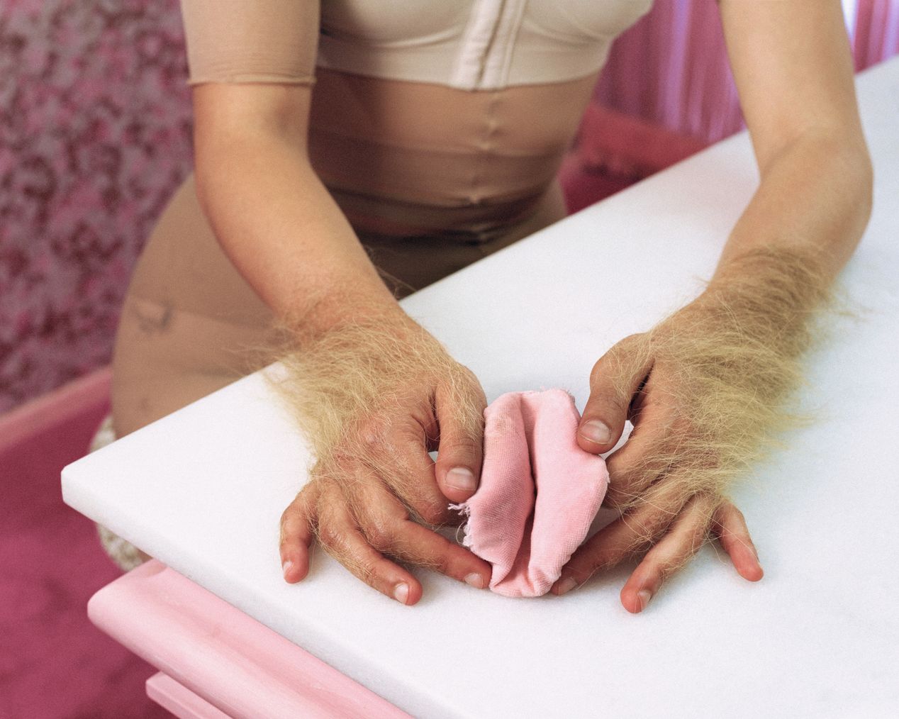 Hands covered with excess hair are holding a pink makeup sponge, art photography, Ilona Szwarc, contemporary Los Angeles artist.